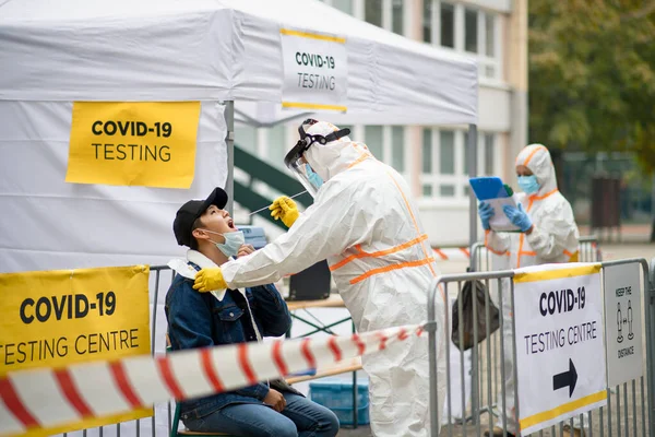 Young man in covid-19 testing center outdoors on street, coronavirus and taking swab concept. — Stock Photo, Image