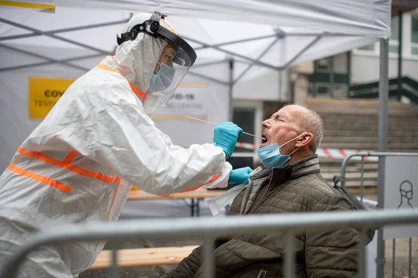 Homem sênior em covid-19 centro de testes ao ar livre na rua, coronavírus e tomando conceito de swab. — Fotografia de Stock