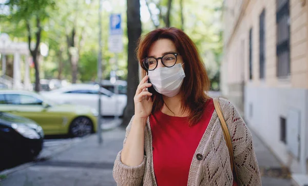 Ώριμη γυναίκα με smartphone περπάτημα σε εξωτερικούς χώρους στην πόλη ή την πόλη, έννοια coronavirus. — Φωτογραφία Αρχείου