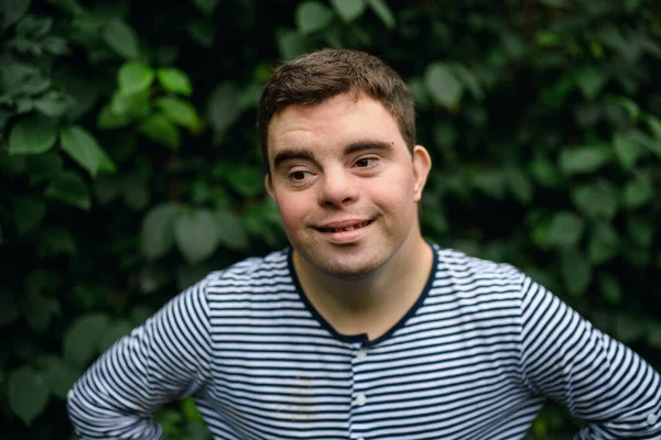 Retrato da síndrome de down homem adulto em pé ao ar livre em fundo verde. — Fotografia de Stock