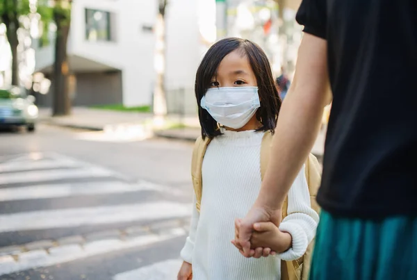 Porträtt av liten japansk flicka med mamma promenader utomhus i stan, coronavirus koncept. — Stockfoto