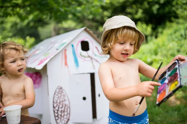 Topless small blond boy and girl with hat painting outdoors in summer. — Stock Photo, Image