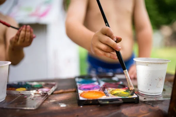 Nerozpoznatelný chlapec a dívka malování venku v létě. — Stock fotografie