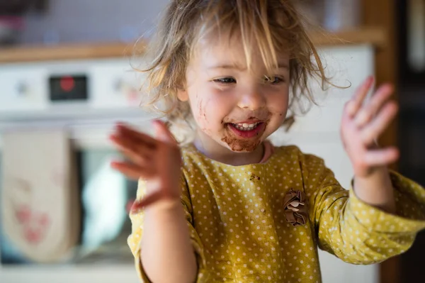 Petite fille avec la bouche sale à l'intérieur dans la cuisine à la maison, applaudissements. — Photo