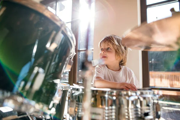 Retrato de niño pequeño dentro de casa, tocando la batería. — Foto de Stock