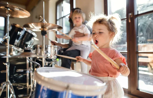 Retrato de niña pequeña dentro de casa, tocando la batería. — Foto de Stock