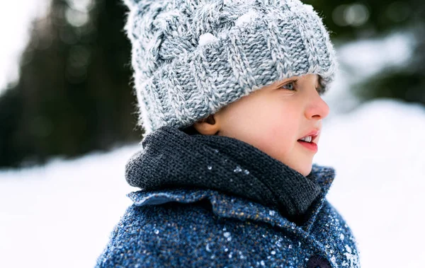 Seitenansicht eines kleinen Kindes, das im Schnee steht, Urlaub in der Winternatur. — Stockfoto