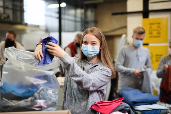 Önkéntesek válogatás adományozott ruhák közösségi jótékonysági adományozási központ, coronavirus koncepció. — Stock Fotó