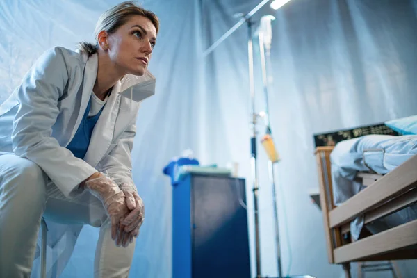 Trött och frustrerad läkare efter patient i sängen på sjukhus, coronavirus koncept. — Stockfoto