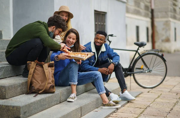 Group of young people outdoors in town, eating pizza. Coronavirus concept. — Stock Photo, Image