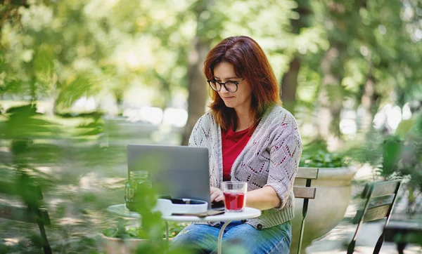 Mujer madura con ordenador portátil al aire libre café de la ciudad, trabajando. —  Fotos de Stock