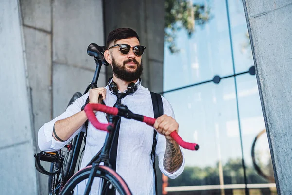 Ung man pendlare med hörlurar och cykel promenader utomhus i staden. — Stockfoto