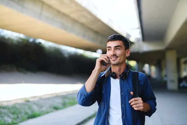 Porträtt av ung attraktiv man med smartphone promenader utomhus i staden. — Stockfoto