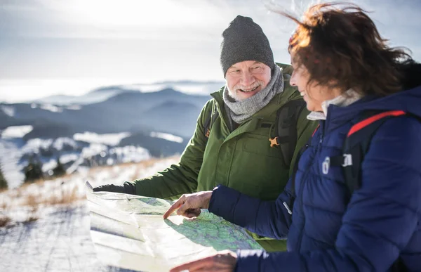 Escursionisti anziani coppia utilizzando la mappa nella natura invernale innevata. — Foto Stock