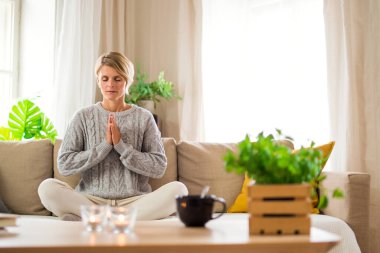 Evde yoga, akıl sağlığı ve meditasyon yapan bir kadının portresi..