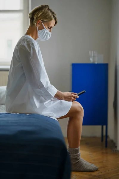 Kvinna patient med smartphone sitter på sängen på sjukhus, psykisk hälsa och coronavirus koncept. — Stockfoto