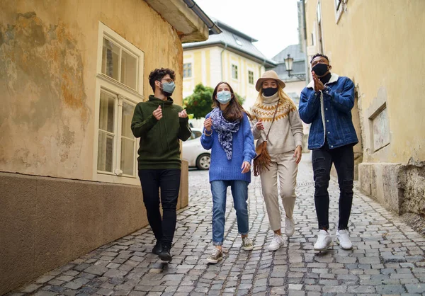 Grupo de jovens com máscara facial ao ar livre na cidade, andando. Conceito de coronavírus. — Fotografia de Stock