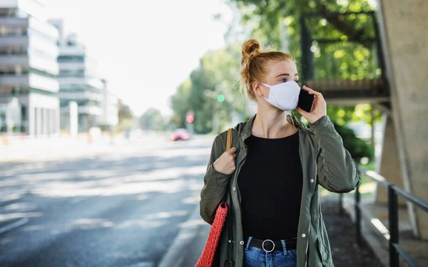 Mladá žena s zrzavými vlasy venku pomocí smartphone ve městě, coronavirus koncept. — Stock fotografie