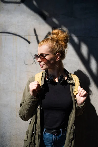 Portrait de jeune femme heureuse aux cheveux roux en ville, portant des lunettes de soleil. — Photo