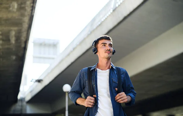 Vista de bajo ángulo del joven atractivo con auriculares al aire libre en la ciudad. —  Fotos de Stock