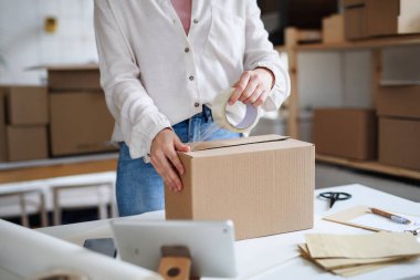 Tanımlanamayan kadın teslimatçı evde çalışıyor, paket paketliyor. Coronavirus konsepti.