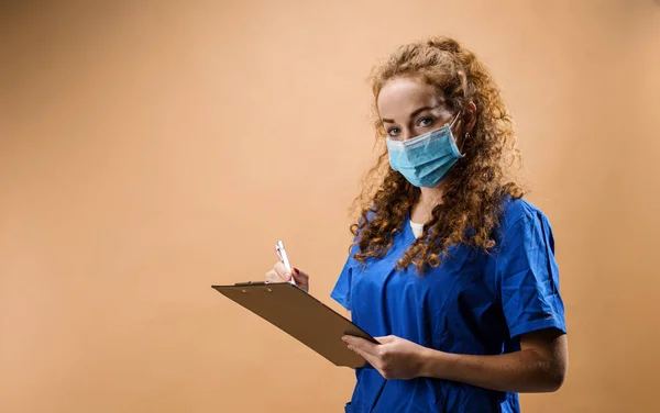 Junge Ärztin in einem Studio mit Klemmbrett, Coronavirus-Konzept. — Stockfoto