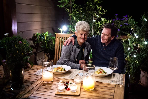 Starší pár na invalidním vozíku večeří večer na terase, dobře se baví. — Stock fotografie