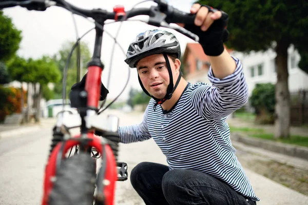 Ritratto della sindrome di Down uomo adulto con bicicletta in piedi all'aperto sulla strada. — Foto Stock