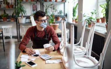 Hüsrana uğramış sahibi kapalı kafede masada oturuyor, Coronavirus yüzünden küçük işletme kilitlenmesi..