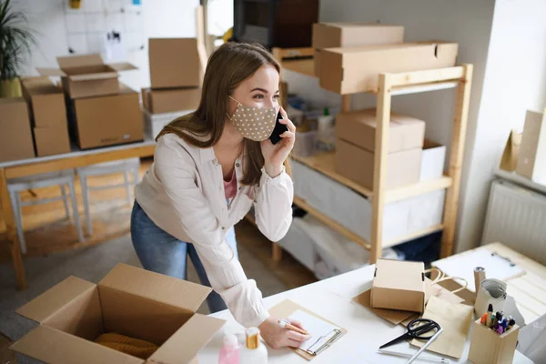 Mujer joven dropshipper con smartphone trabajando en casa, concepto coronavirus. — Foto de Stock