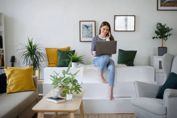 Jeune étudiant avec ordinateur portable et smartphone travaillant à la maison, concept coronavirus. — Photo