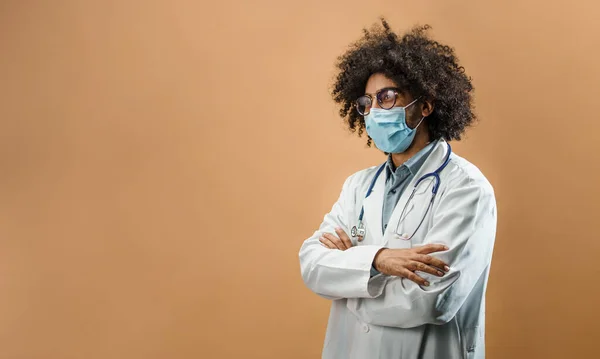 Sorgsen mogen man läkare med ansiktsmask i stående i studio, coronavirus koncept. — Stockfoto
