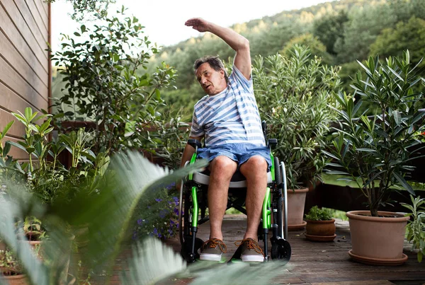 Homem sênior em cadeira de rodas fazendo exercício no terraço. — Fotografia de Stock