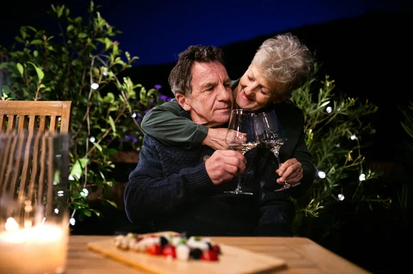 Senior par på kvällen på terrassen, dricka vin. — Stockfoto