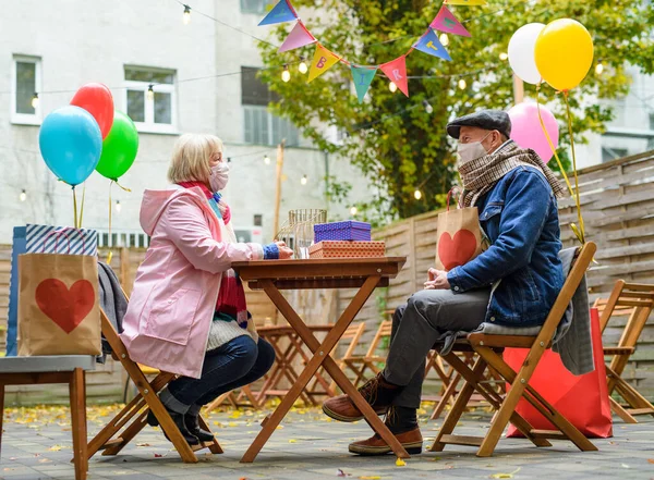 Счастливые старшие партнеры в уличном кафе в городе, пара празднует день рождения. Коронавирусная концепция. — стоковое фото