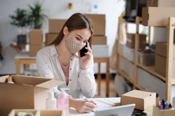 Young woman dropshipper with smartphone working at home, coronavirus concept. — Stock Photo, Image