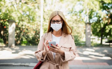 Şehirdeki ya da kasabadaki caddeden karşıya geçen son sınıf öğrencisi kadın, Coronavirus konsepti..