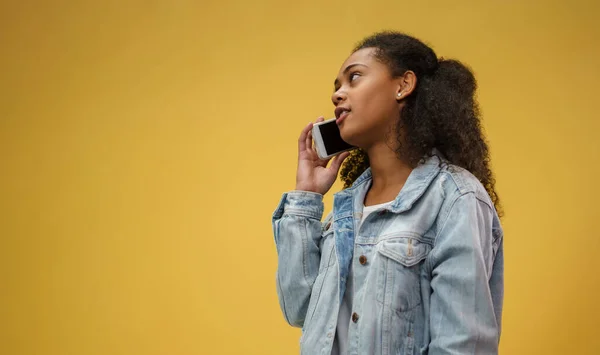 Młoda nastolatka w studio na żółtym tle, za pomocą smartfona. — Zdjęcie stockowe