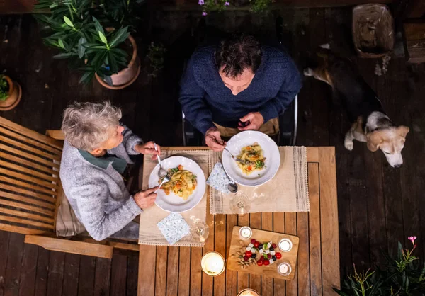 Widok z góry para seniorów na wózku inwalidzkim przy kolacji wieczorem na tarasie. — Zdjęcie stockowe