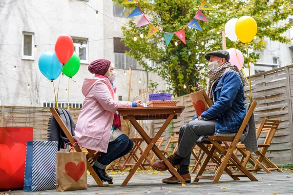 Ευτυχισμένοι ανώτεροι συνεργάτες σε υπαίθρια καφετέρια στην πόλη, ζευγάρι γιορτάζει τα γενέθλια. Έννοια του Coronavirus. — Φωτογραφία Αρχείου