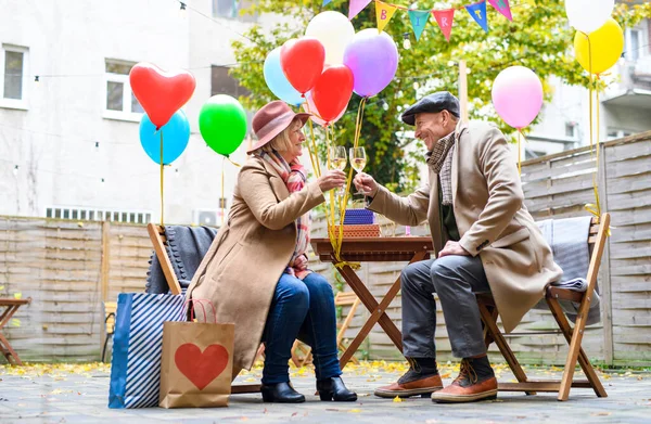 Ευτυχισμένο ζευγάρι ηλικιωμένων με κρασί σε υπαίθριο καφέ στην πόλη, γιορτάζοντας τα γενέθλια. — Φωτογραφία Αρχείου