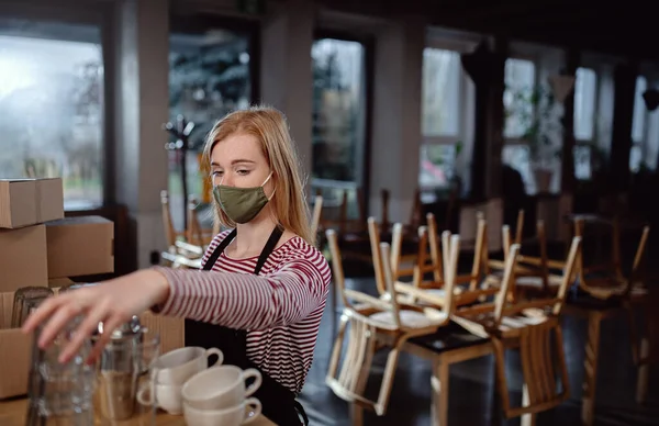 Ägare sätta koppar och glas i lådor i stängt café, småföretag låsning på grund av coronavirus. — Stockfoto