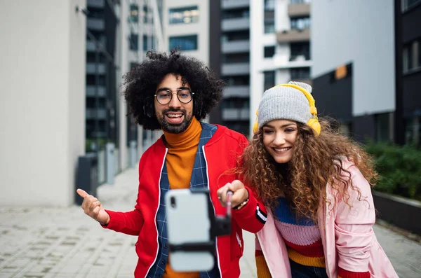Jeune couple avec smartphone faire de la vidéo en plein air sur la rue, tik tok concept. — Photo
