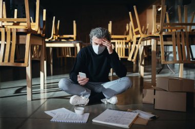 Hüsrana uğramış sahibi, Coronavirus yüzünden küçük işletme kilitlenmesi yüzünden kapalı bir kafede oturuyor..