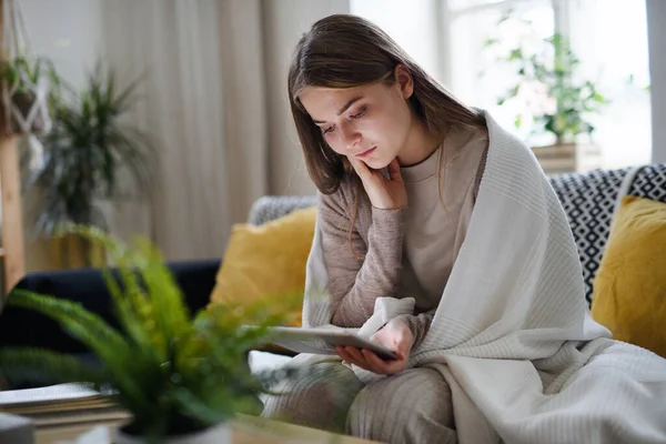 Mujer joven preocupada con manta usando tableta en casa, concepto de coronavirus. — Foto de Stock