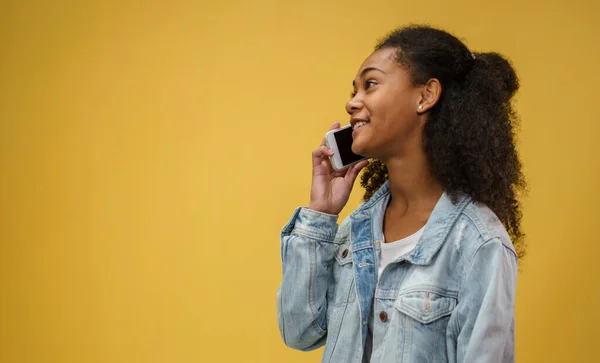 Jovem adolescente em um estúdio no fundo amarelo, usando smartphone. — Fotografia de Stock