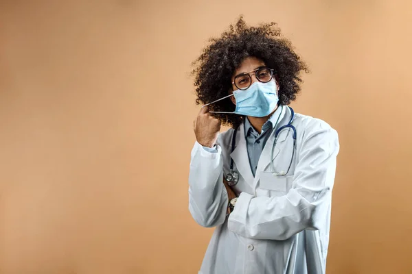 Happy mature man doctor with face mask in standing in studio, coronavirus concept. — Stock fotografie