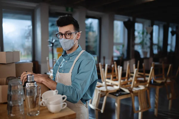 Разочарованный официант упаковывает стаканы в закрытое кафе, закрывает малый бизнес из-за коронавируса. — стоковое фото