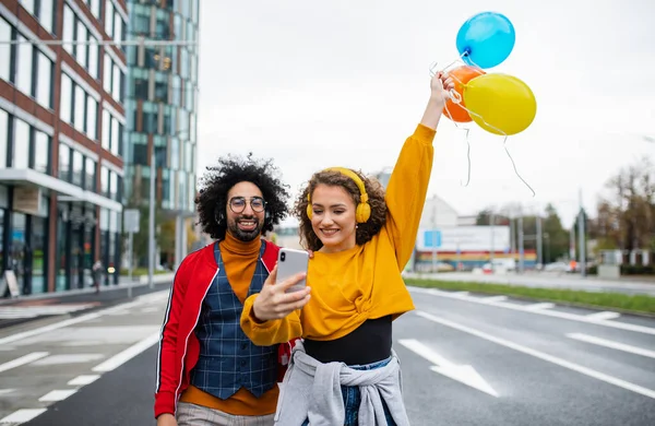 Jovem casal com smartphone fazendo vídeo para mídias sociais ao ar livre na rua. — Fotografia de Stock