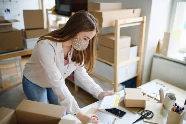 Mujer joven dropshipper con tableta trabajando en casa, concepto coronavirus. — Foto de Stock